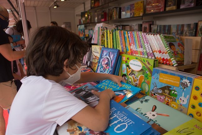 Archivo - Un niño ojea libros en la Feria del Libro de Mérida.