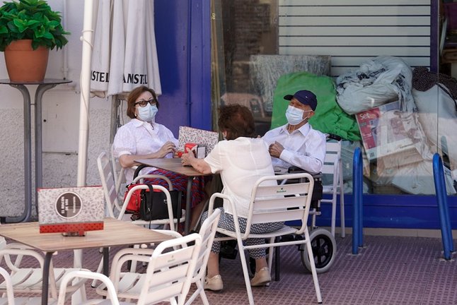 Ancianos con mascarilla conversan sentados en la terraza de un bar, a 27 de julio de 2021, en Madrid, (España).