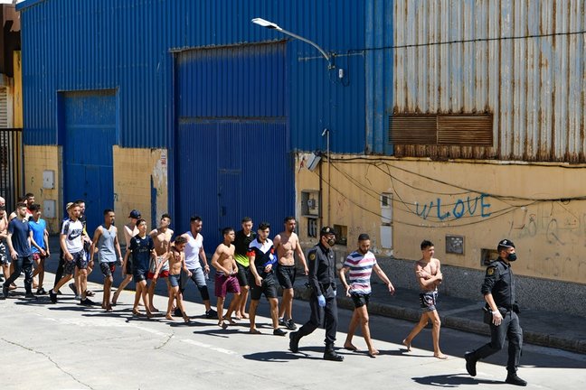 Archivo - Un grupo de jóvenes migrantes marroquíes en fila en las inmediaciones de una nave, a 17 de mayo de 2021, en Ceuta (España). La delegación ha cifrado que unas 1000 personas, de las que al menos 300 son menores de edad, han conseguido sortear los 