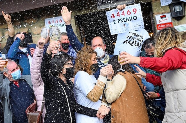Varias personas celebran parte del segundo premio correspondiente al sorteo de la lotería de El Niño, este jueves en la localidad cántabra de Treceño. EFE/Pedro Puente Hoyos