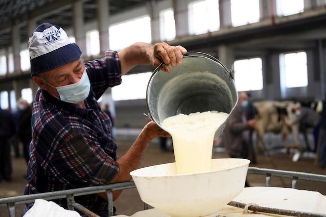 TORRELAVEGA (CANTABRIA) 21/04/2021.- Un hombre almacena la leche recién ordeñada, este miércoles en el Mercado Nacional de Ganados de Torrelavega. EFE/Pedro Puente Hoyos