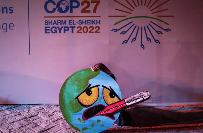 Una activista sostiene una imagen de la Tierra representada como una cara enferma, en la COP27 de Sharm El-Sheikh, Egipto. EFE/EPA/Sedat Suna