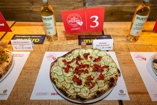 La pizza vegana con crema de pistacho, calabacín, tomate confitado, panko y ralladura de lima de Hot Now (Madrid) ha sido elegida como la mejor de España en una final en la que han competido ocho 'pizzaioli' seleccionados por el jurado entre las 19 propuestas presentadas. EFE/Madrid Fusión SOLO USO EDITORIAL/SOLO DISPONIBLE PARA ILUSTRAR LA NOTICIA QUE ACOMPAÑA (CRÉDITO OBLIGATORIO)

La pizza vegana con crema de pistacho, calabacín, tomate confitado, panko y ralladura de lima de Hot Now (Madrid) ha sido elegida como la mejor de España en una final en la que han competido ocho 'pizzaioli' seleccionados por el jurado entre las 19 propuestas presentadas. EFE/Madrid Fusión