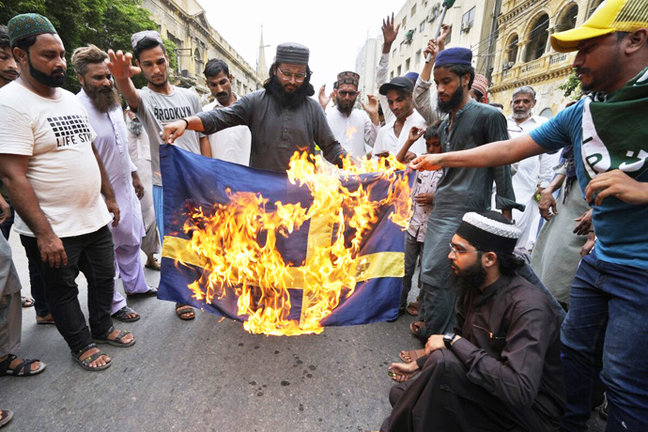 partidarios del partido radical islamista Tahrik-e-Labaik de Pakistán queman una bandera de Suecia.