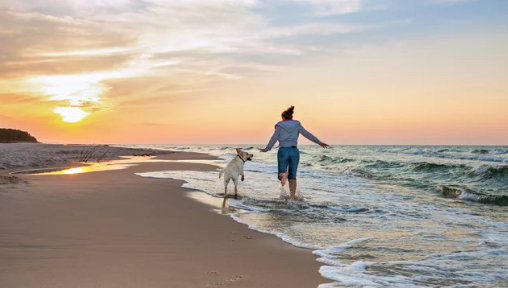 Una mujer corre por la playa con su perro. / A.S.