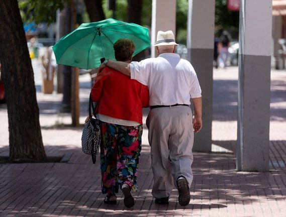 Dos personas mayores caminan bajo la sombra de un árbol. Eduardo Parra / Archivo