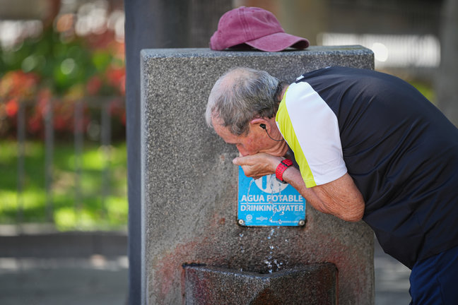 Un hombre se refresca en fuente pública debido a las altas temperaturas. / María José López