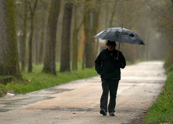 Un señor paseando bajo la lluvia con su paraguas. / A.E.