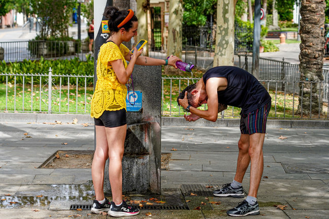 Dos personas refrescándose en una fuente. / EP